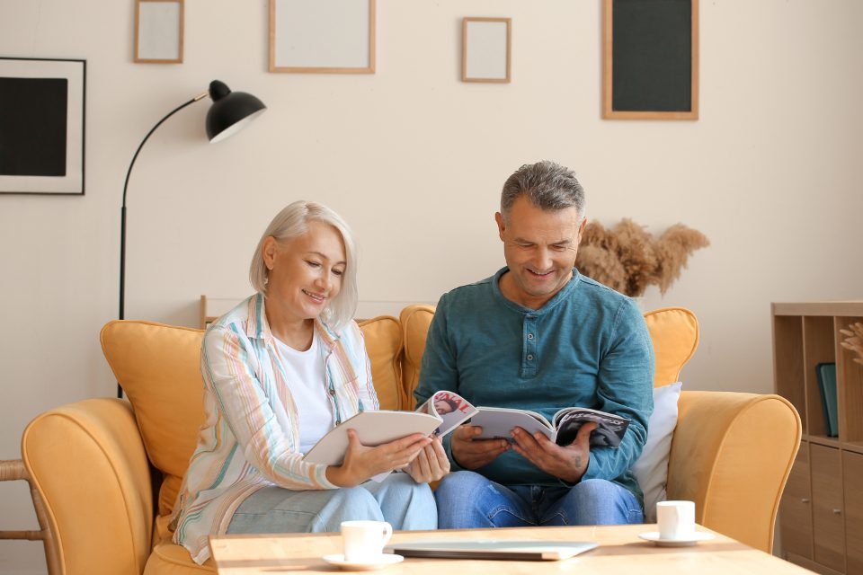 An older couple sitting together reading at home